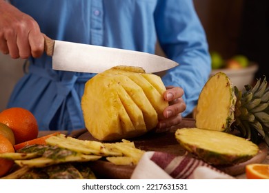 Crop Anonymous Person With Knife Cutting Fresh Pineapple On Wooden Board While Preparing Healthy Snack In Kitchen