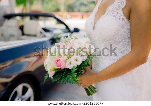 Crop bride with flowers near\
car