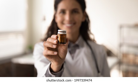 Crop close up blurred background of female doctor hold bottle medication prescribe pills to sick patient. Woman GP or therapist recommend good quality medicines. Healthcare, treatment concept.