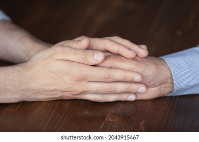 Crop Close Up Caring Young Man Grownup Son Touching Old Father Or Grandfather Hand On Wooden Table, Caucasian Caregiver Supporting Comforting Senior Mature Patient, Family Relationship Concept