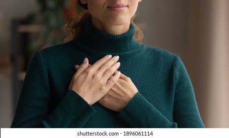 Crop Close Up Of Caucasian Woman Hold Hands In Prayer At Heart Chest Feel Religious Superstitious. Young Female Believer Being Grateful Thankful Pray To God. Faith, Belief, Religion Concept.