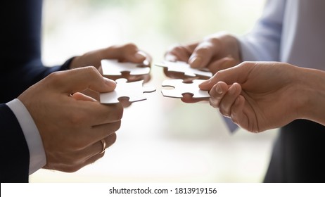 Crop close up of diverse colleagues hold assemble jigsaw find business solution together. Hands of people put join puzzle pieces, involved in teambuilding activity in office. Teamwork concept - Shutterstock ID 1813919156