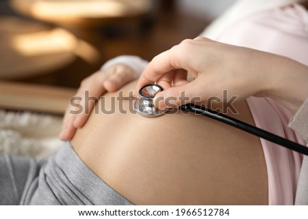 Crop close up of doctor hold stethoscope listen to pregnant woman baby bump, check kid in womb. Nurse or gynecologist use phonendoscope examine child in belly heartbeat. Pregnancy concept.