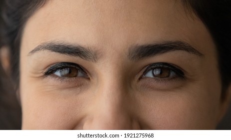 Crop close up of eyes of smiling young Indian woman look at camera feel optimistic satisfied. Closeup of happy millennial mixed race ethnicity female. Diversity, ethnic, wide view concept. - Shutterstock ID 1921275968