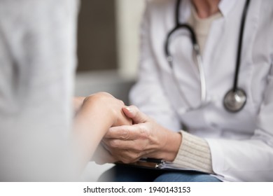 Crop close up of female nurse or therapist hold patient hands show support and care at consultation. Supportive woman doctor comfort caress sick client in clinic. Healthcare, medicine concept.