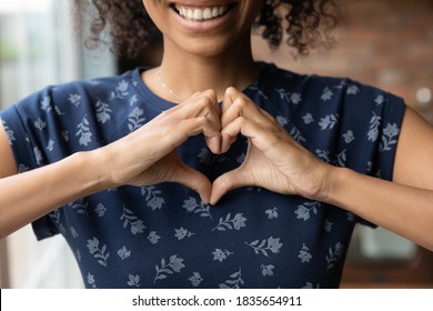 Crop close up of happy African American woman feel grateful thankful show heart sign spread love and care. Smiling biracial female volunteer make hand gesture support ill sick people patients. - Shutterstock ID 1835654911