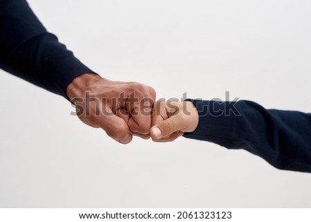Crop close up image of father and son give fists bump show family unity and support. Dad and boy child kid make hand gesture nonverbal sign show mutual support respect in family relations.