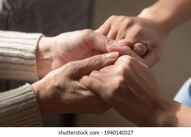 Crop close up of loving elderly mother hold hands of adult daughter show support and care. Supportive mature mom parent comfort caress millennial grownup child. Family unity, bonding concept.
