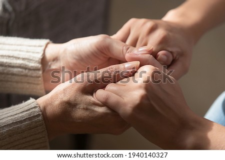 Crop close up of loving elderly mother hold hands of adult daughter show support and care. Supportive mature mom parent comfort caress millennial grownup child. Family unity, bonding concept.