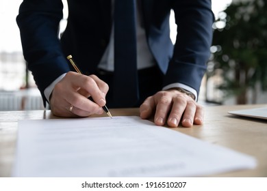 Crop Close Up Of Male CEO Or Boss In Suit Stand In Office Put Signature On Paper Document Making Agreement. Businessman Sign Paperwork Close Business Financial Deal At Workplace. Legislation Concept.