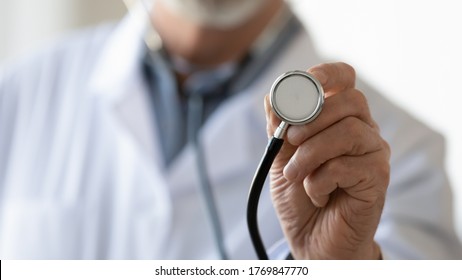 Crop close up of male doctor in white medical uniform hold stethoscope examine check patient, man GP or physician therapist use medical equipment for checkup in clinic or hospital, healthcare concept