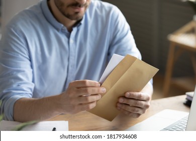 Crop close up of man sit at desk open envelope with paper letter or correspondence at office. Male worker get postal paperwork or notice notification at workplace, receive message or invitation. - Shutterstock ID 1817934608