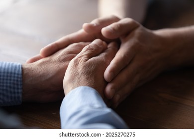 Crop close up of old Caucasian father and adult son hold hands show family unity and support. Supportive mature dad and grownup child demonstrate love care, comfort and caress. Bonding concept.