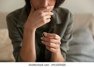 Crop close up of upset woman hold wedding ring think of marriage dissolution or divorce having family problems. Unhappy sad female stressed with relationships end or breakup. Relations, love concept.