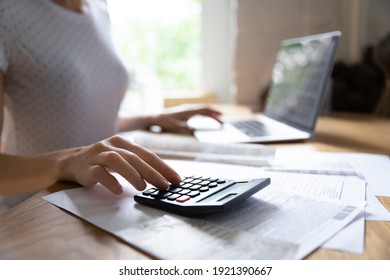 Crop close up of woman calculate on calculator manage family budget make payment on computer. Female busy take care of household expenses expenditures, paying bills on laptop online. Saving concept.
