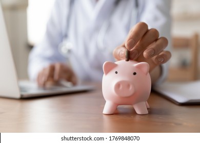 Crop Close Up Of Woman Doctor Hand Put Coin In Piggybank, Make Monetary Donation To Clinic Fund, Female Drop Money Contribution Or Volunteer Charity In Piggy Bank For Patient Or Hospital Need Care