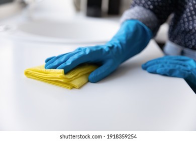 Crop Close Up Of Woman In Rubber Gloves Clean Counters In Kitchen. Female Housekeeper Or Housewife Do Daily Home Cleaning Routine Use Napkin Wipe Dust And Mud From Table Or Desk. Housekeeping Concept.