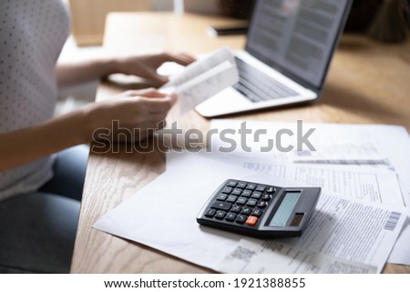 Crop close up of woman sit at desk manage household expenses expenditures paying bills on laptop online. Female calculate home family budget, make payment on computer on internet. Saving concept.