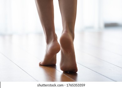 Crop close up of young woman with bare feet walk on warm wooden floor at home or hotel, healthy female step barefoot in apartment indoors, underfloor heating, spa procedure concept