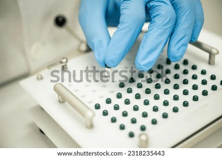 Crop compounding pharmacist putting pill into capsule filler