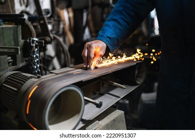 Crop craftsman sanding metal on belt - Powered by Shutterstock