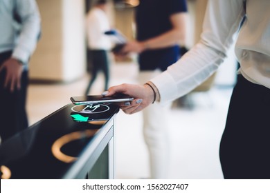 Crop elegant female in formal wear swiping smartphone while passing through automatic access control in modern office.  Electronic identification pass system. Advanced technology  - Powered by Shutterstock