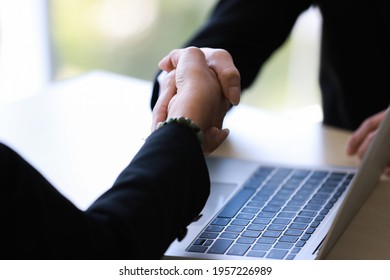 Crop Female Entrepreneur Shaking Hand Of Partner Over Laptop After Striking Deal During Meeting In Office. Business Success And Negociation Concept.