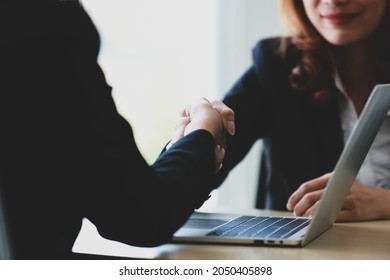 Crop Female Entrepreneur Shaking Hand Of Partner Over Laptop After Striking Deal During Meeting In Office. Business Success And Negociation Concept.