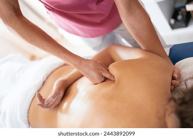 Crop female osteopathic therapist massaging back of patient - Powered by Shutterstock