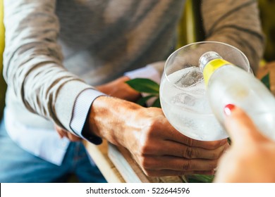 Crop hands pouring tonic in cocktail glass. 