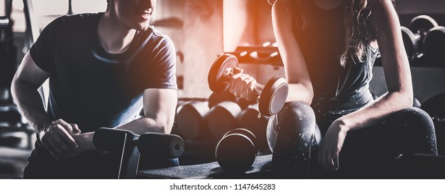 Crop image of beautiful sport girl with dumbbell in hand with personal trainer in professional gym, color filter effect selective focus. - Shutterstock ID 1147645283