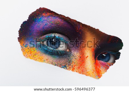 Crop image of female eyes with colorful powder make up looking to camera on white background. Beautiful fashion model with creative art makeup. Abstract colourful splash make-up. Holi festival