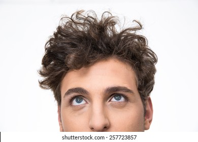 Crop image of a handsome young man with curly hair looking up at copyspace