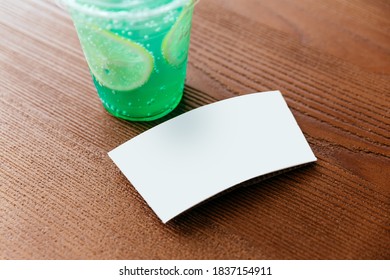 Crop Image Of The White Cup Sleeve Of Green Iced Soda With Sliced Lemon On A Wooden Table. Cup Sleeve Template.