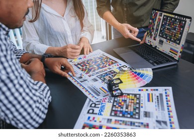 Crop image of worker checking print quality of media graphics proof print in printing industry. Selected focus