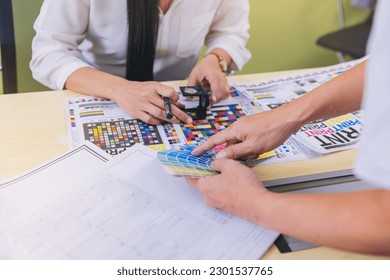 Crop image of worker checking print quality of media graphics proof print and color tone in printing industry. Selected focus