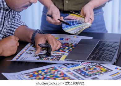 Crop image of worker checking print quality of media graphics proof print and color tone in printing industry. Selected focus
