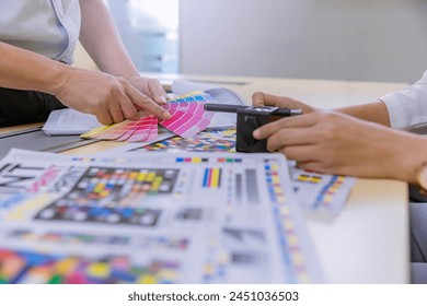 Crop image of worker checking print quality of media graphics proof print and color tone in printing industry. Selected focus