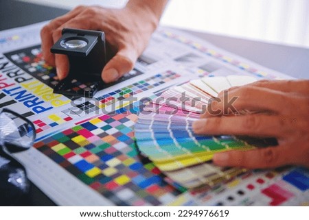 Crop image of worker checking print quality of media graphics proof print and color tone in printing industry. Selected focus	