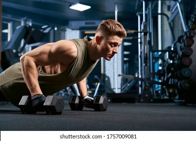 Crop of muscular caucasian man training on floor using dumbbels in sports club. Close up of young sportsman building muscles, doing push ups in empty gym. Concept of sport, bodybuilding. - Powered by Shutterstock