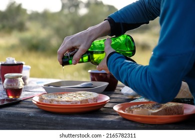 Crop Person Pouring Oil On Toast In Countryside