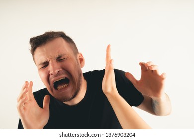 Crop person slapping scared man in face. Emotional male getting slapped in face while shouting with closed eyes in fear on white background
