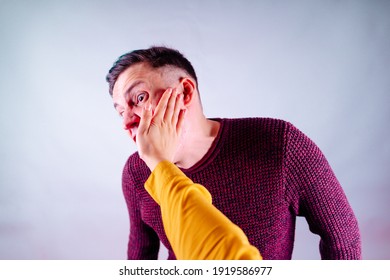 Crop person slapping scared man in face. Emotional male getting slapped in face while shouting with closed eyes in fear on white background.