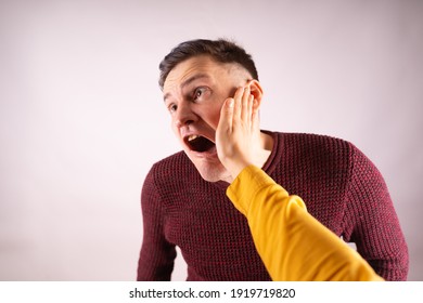 Crop person slapping scared man in face. Emotional male getting slapped in face while shouting with closed eyes in fear on white background.