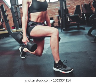 Crop photo Fit girl doing exercise lunges with dumbbells in her hands at gym
