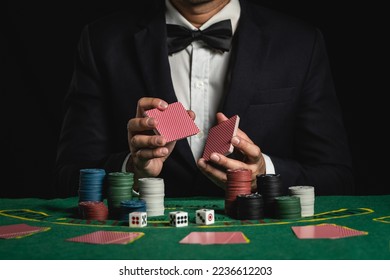 Crop picture of close up man dealer or croupier shuffles poker cards betting in casino on black background of green table, Dealer man invitation bet playing cards. Casino, poker, poker game concept
