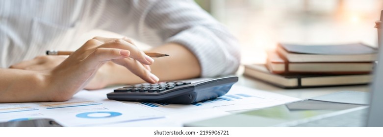 Crop Shot Of Business Woman Checks Her Work And Uses A Calculator To Calculate Her Annual Financial Statements. Turnover And Profit Balance Sheet Making Financial Records In Paper Audits.