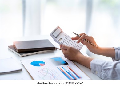 Crop Shot Of Business Woman Checks Her Work And Uses A Calculator To Calculate Her Annual Financial Statements. Turnover And Profit Balance Sheet Making Financial Records In Paper Audits.