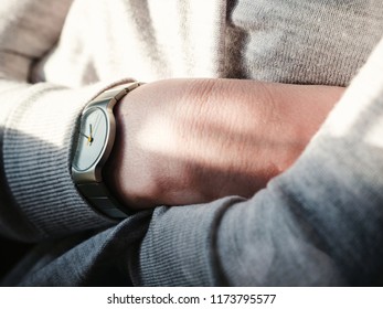 Crop shot in closeup of woman holding arms crossed with modern steel titanium wristwatch on hand in sunlight
