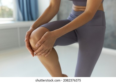 Crop shot of random Caucasian woman doing yoga in lilac crop top and leggings, touching gently right knee, balancing on left foot, having cute abdominal folds, isolated over fitness studio background - Powered by Shutterstock